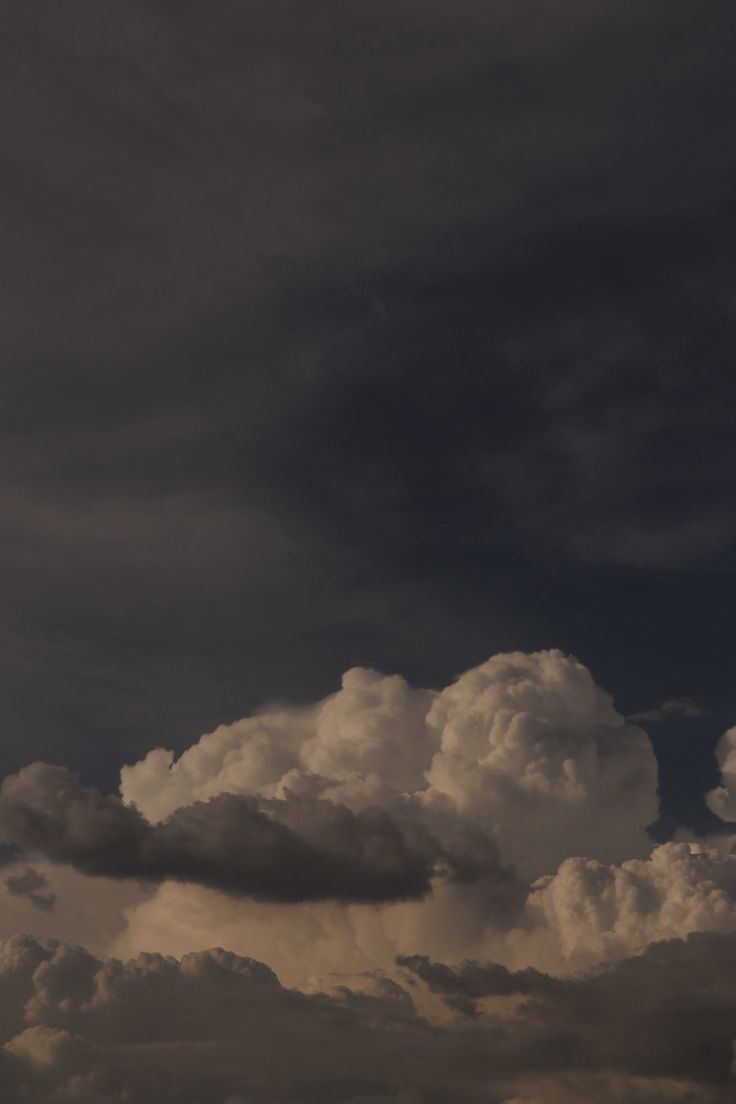 the airplane is flying high in the sky with many clouds behind it and one plane on the ground