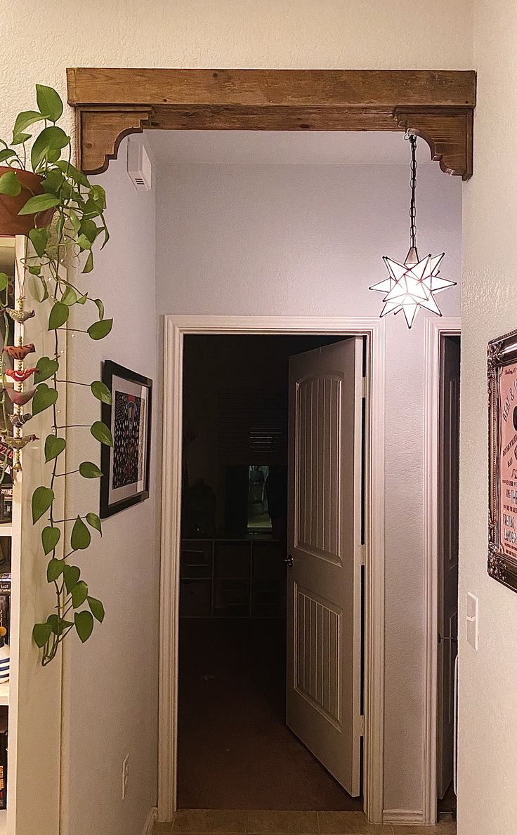 an entry way with a clock on the wall and a plant hanging from the ceiling