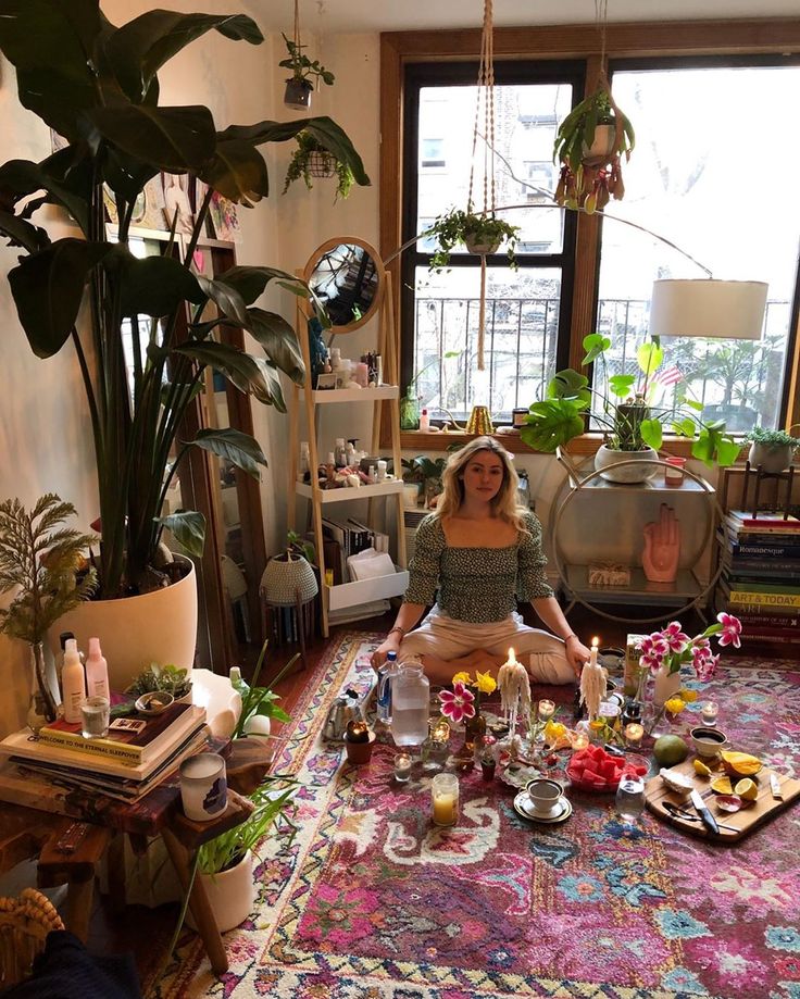 a woman is sitting in the middle of a room surrounded by plants and other things