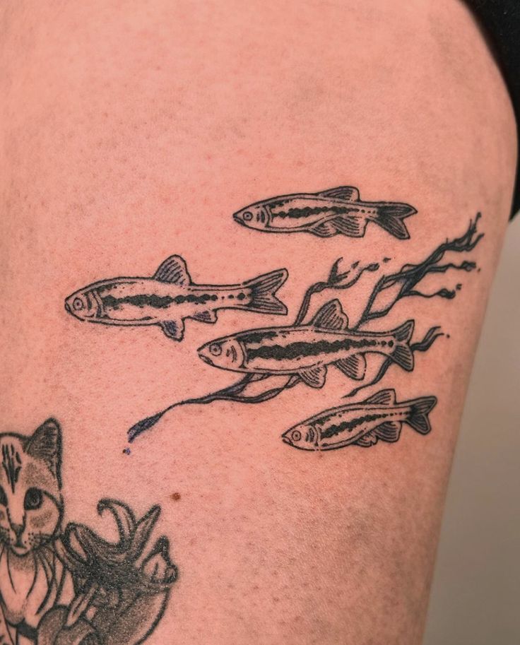 a cat and fish tattoo on the thigh