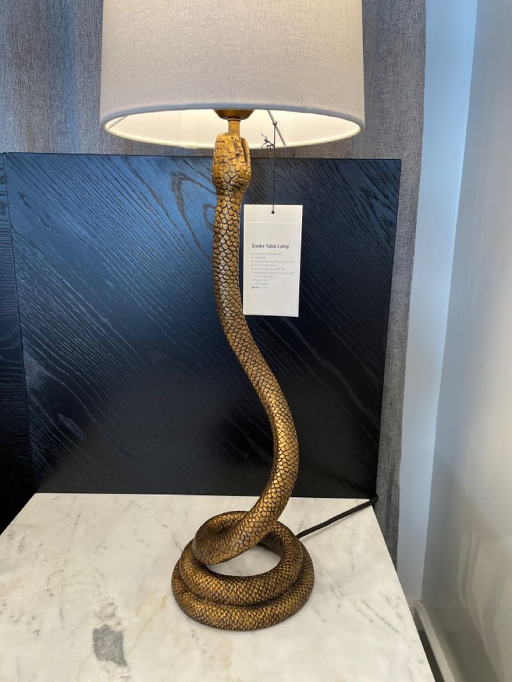 a snake lamp on a table with a price tag hanging from it's side