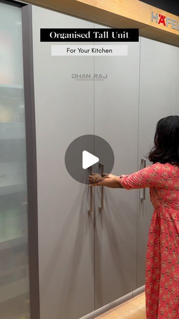 a woman is opening the door to a stainless steel kitchen cabinet that has glass doors on both sides