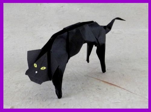 a black cat made out of paper with yellow eyes on it's head and tail