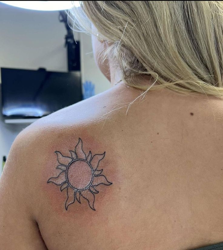 a woman with a sun tattoo on her back