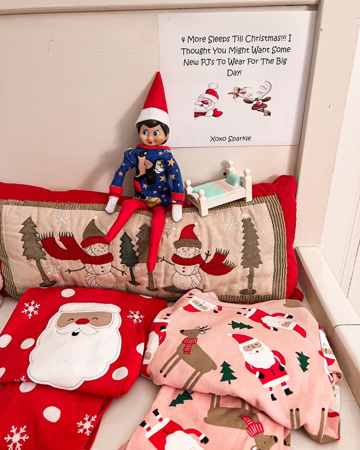 an elf is sitting on top of the bed with his christmas themed comforter and pillows