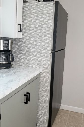 a kitchen counter with a coffee maker on top and a refrigerator in the back ground