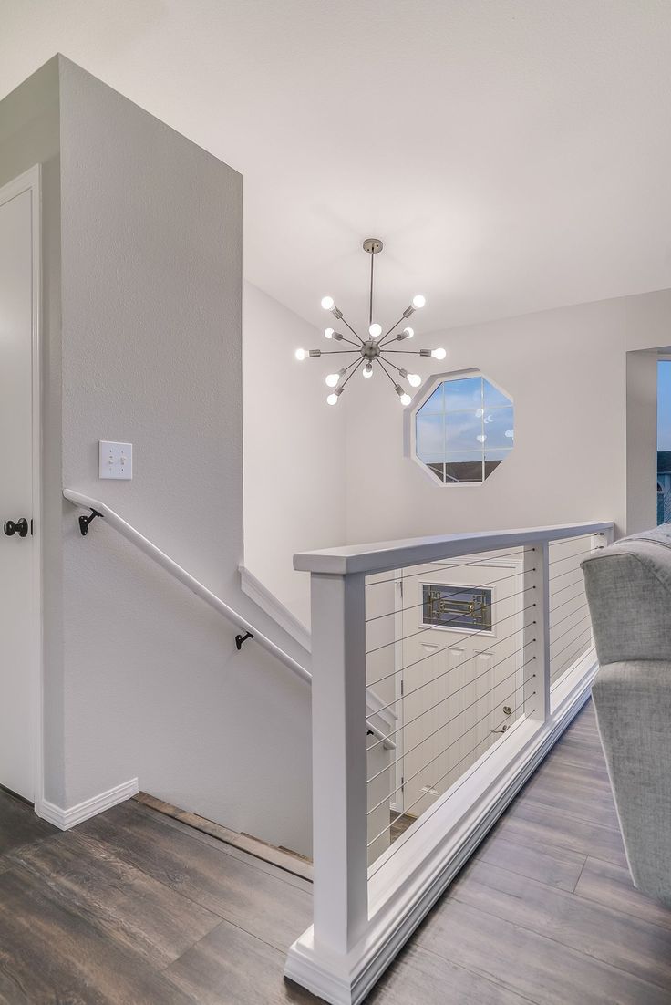 an empty living room with stairs leading up to the second floor, and a chandelier hanging from the ceiling