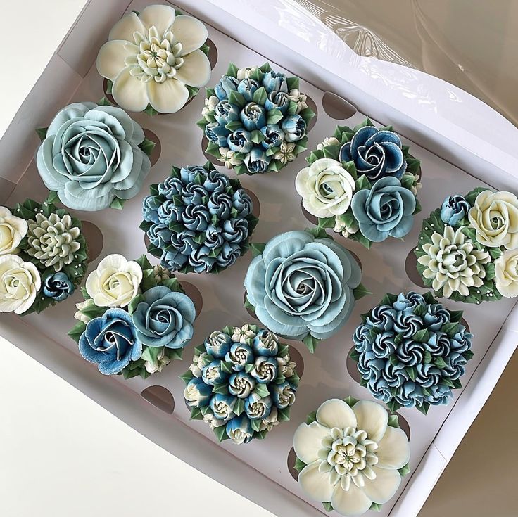 cupcakes decorated with blue and white flowers in a box