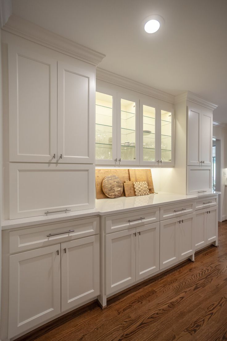 a kitchen with white cabinets and wood floors