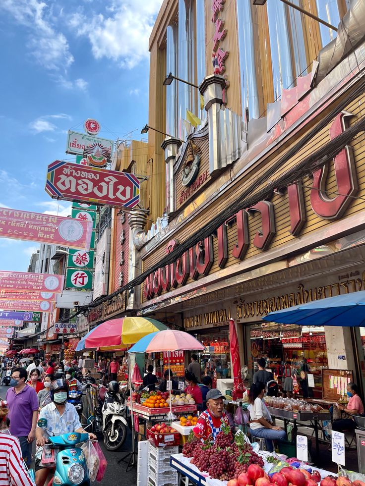 many people are shopping at an outdoor fruit and veggie market in the city