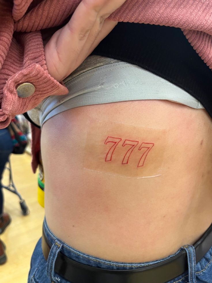 777 in red outline tattoo Meaning Of 777, 777 Tattoos, 777 Angel Number Tattoo, 777 Tattoo Meaning, 777 Angel Number, 777 Tattoo, Angel Number Tattoo, Red Outline, Ribcage Tattoo