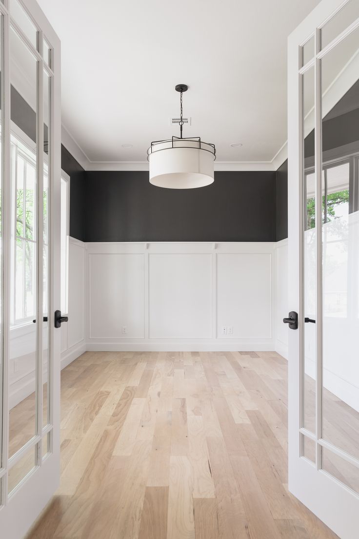 an empty room with black walls and white trim on the door, wood flooring