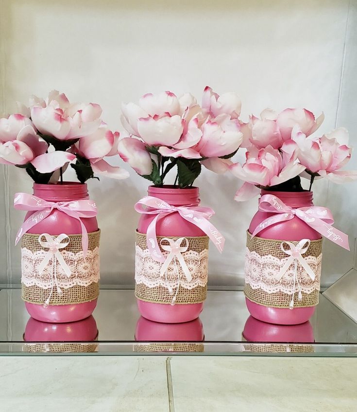 three pink vases with flowers in them sitting on a table