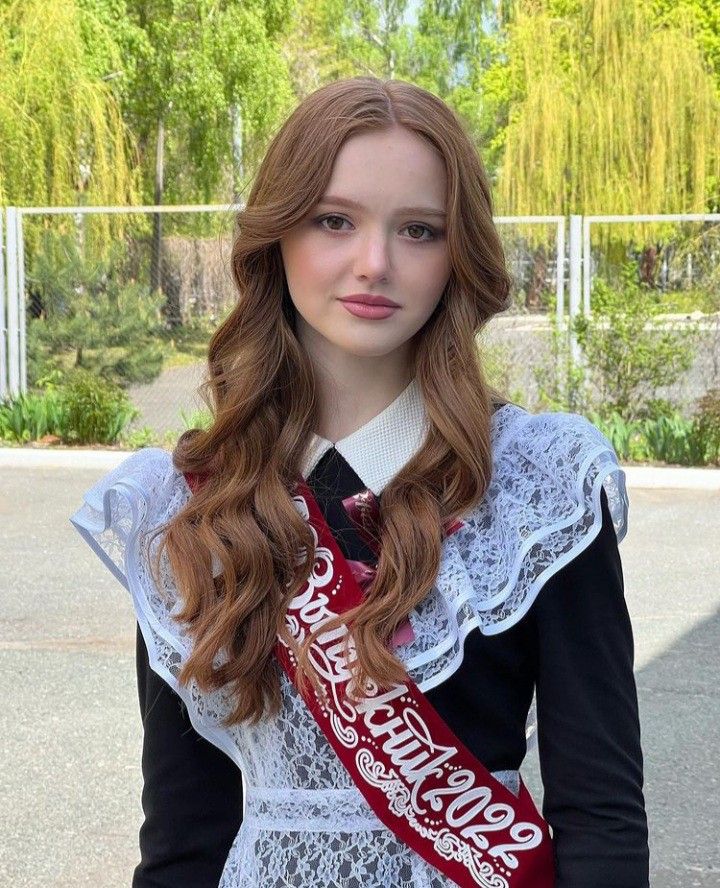 a woman with long red hair wearing a white dress and holding a coca cola tie