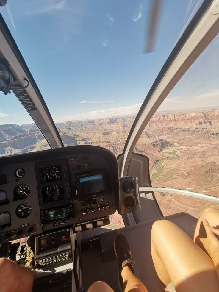 two people sitting in the cockpit of an airplane looking out over canyons and mountains