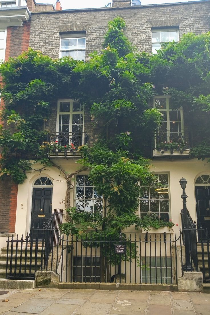 an old building with ivy growing on it's windows and gated in area