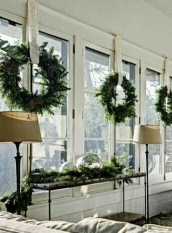 a living room filled with lots of windows covered in christmas wreaths and greenery