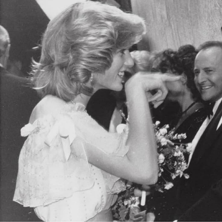 an old black and white photo of two people smiling at each other with flowers in their hands