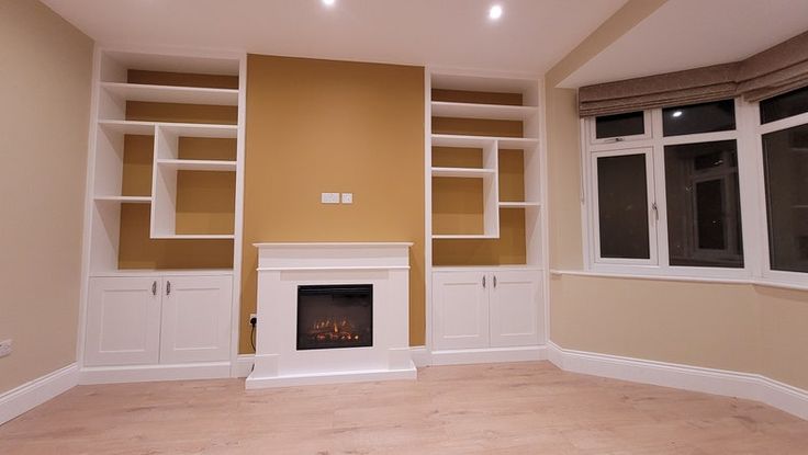 an empty living room with built - in bookcases and a fireplace