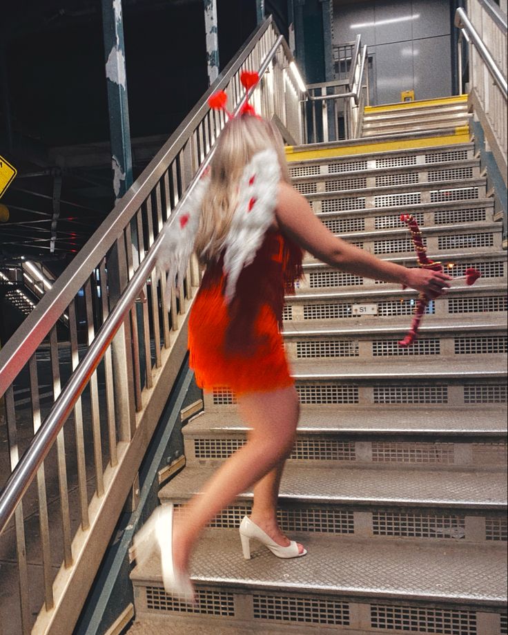 a woman in red and white is walking down some stairs with her hand on the railing