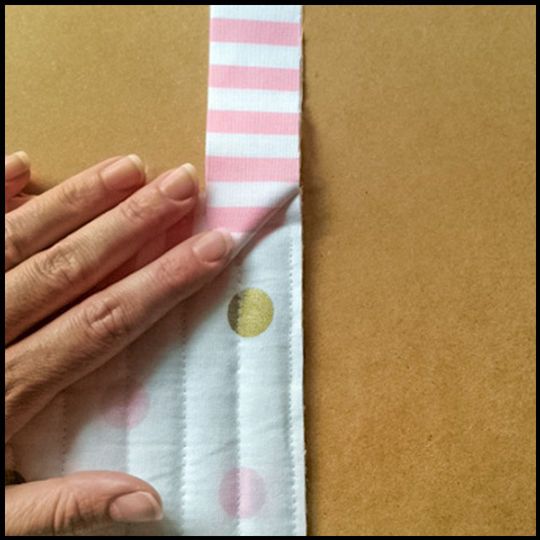 someone is peeling the edge of a pink and white polka dot ribbon with their hands