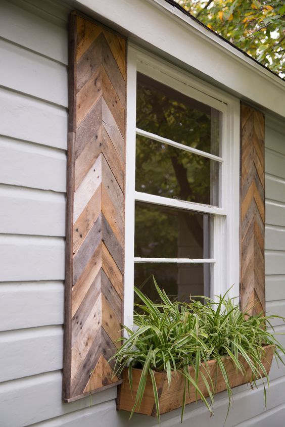 an old window with wooden shutters and plants in the window box on the side of a house