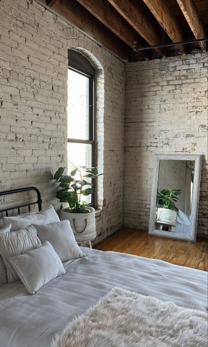 a white bed sitting next to a window with a mirror on it's side