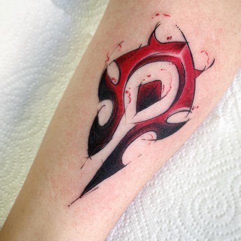 a red and black tattoo design on the arm