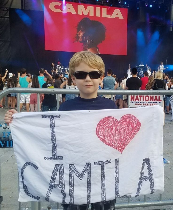 a young boy holding up a sign with the words i love campila written on it