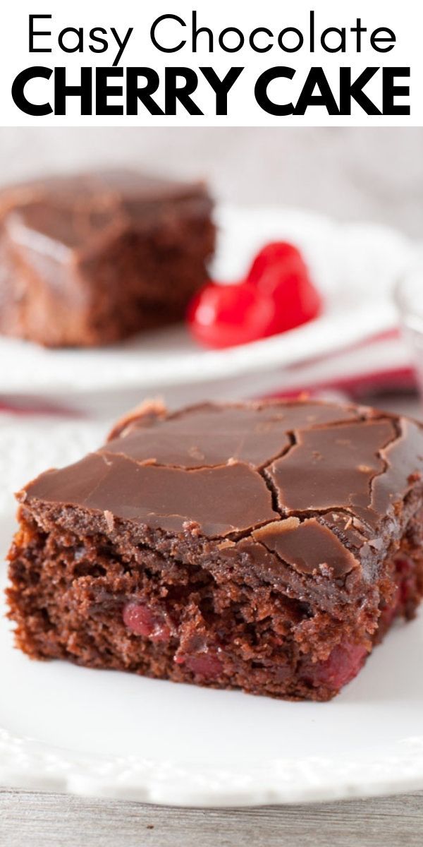 two pieces of chocolate cherry cake on a white plate with strawberries in the background