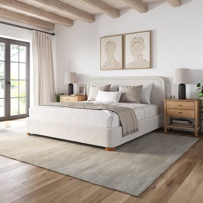 a large white bed sitting in a bedroom on top of a hard wood flooring