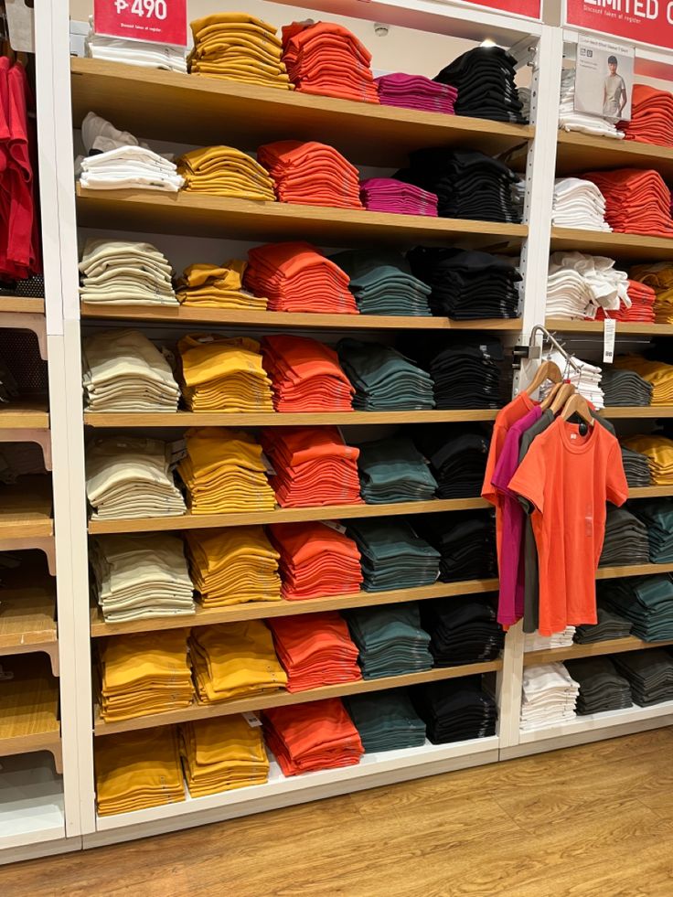 there are many shirts on the shelves in this store, all different colors and sizes