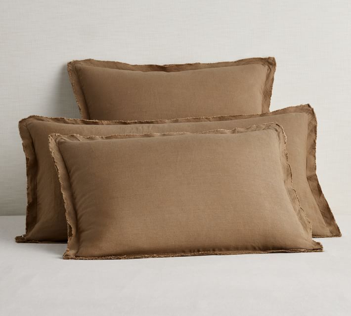 three brown pillows with ruffled edges on a white bedding set, one is plain and the other is plain