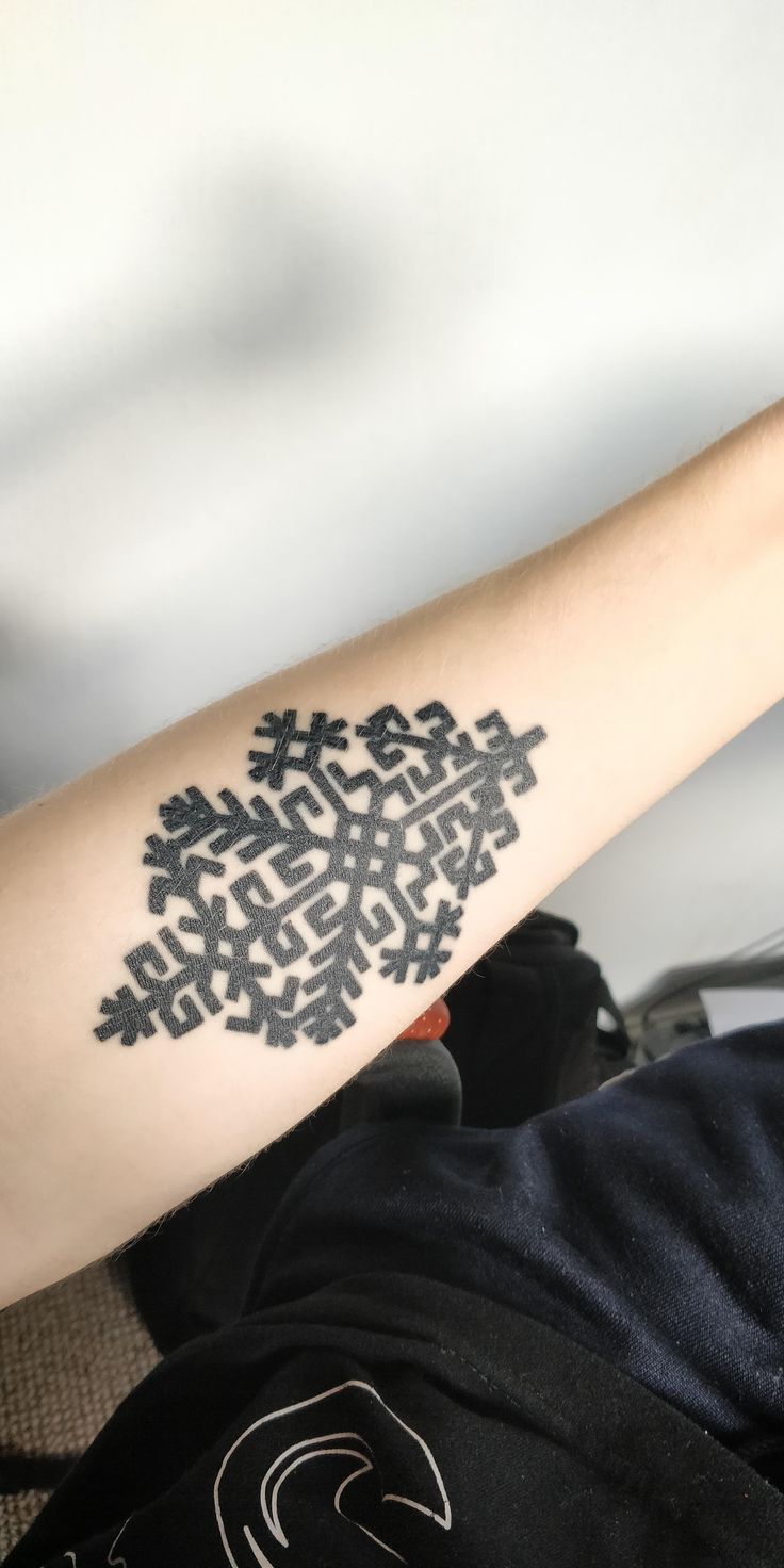 a person with a tattoo on their arm that has an image of a snowflake