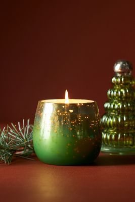 a green candle sitting next to a christmas tree