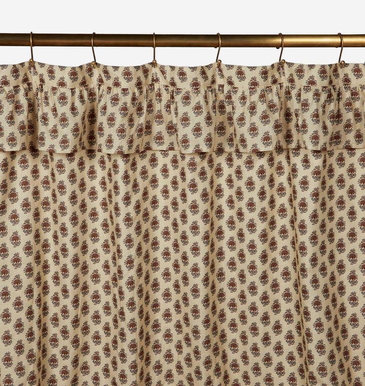 the curtain is hanging on a rod and has a flower pattern in brown, beige and white