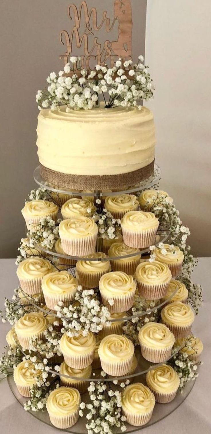 a three tiered cake with cupcakes and baby's breath on top