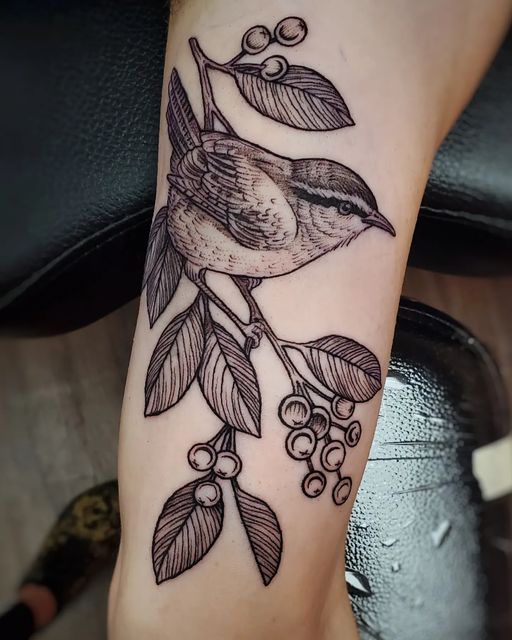 a bird sitting on top of a tree branch with leaves and berries around its neck