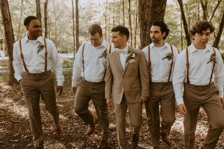 a group of young men standing next to each other in the middle of a forest