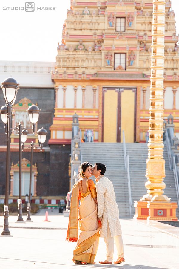 two people standing next to each other in front of a building with columns and lights