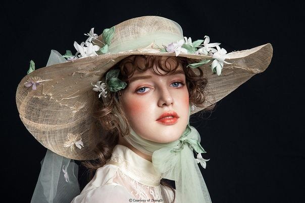 a woman wearing a large hat with flowers on it's brim and veil