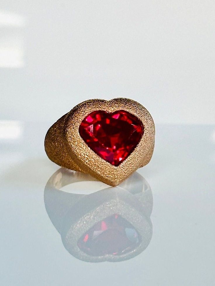 With its sentimental and sweet vibe this ruby signet ring is a modern take on the universal symbol of love. Perfect for everyday or special occasions it adds a fun element to any look. Ring face 17mm x 18mm Ruby 12mm x 11mm Set in 9K hand finished textured rose gold. Can be customized to polished and brushed finish. Weight  9.50-11 grams. Please contact us for sizing options. Follow us on Instagram: https://www.instagram.com/missionewyork/ Heart-shaped 14k Gold Ruby Promise Ring, Valentine's Day Gold Ruby Ring, Gold Ruby Ring For Valentine's Day, Red 14k Gold Heart Promise Ring, Red 14k Gold Heart Ring For Promise, 14k Gold Red Heart Ring For Promise, Valentine's Day Yellow Gold Ruby Promise Ring, Valentine's Day Heart Cut Signet Ring, Valentine's Day Heart Cut Signet Promise Ring