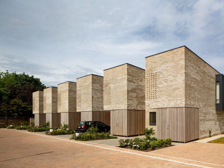 a row of brick buildings sitting next to each other on a sidewalk near a parking lot