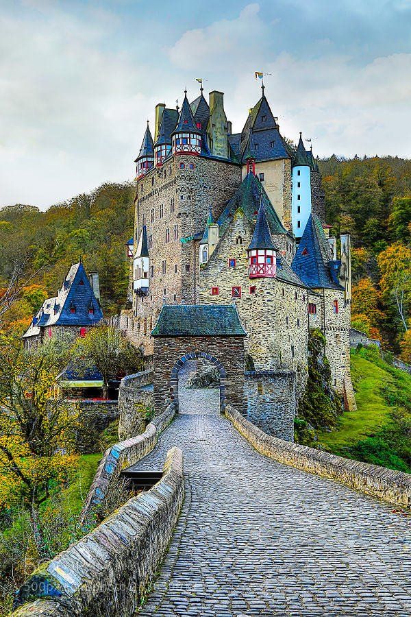 an old castle is shown on the side of a hill with cobblestone roads