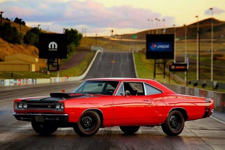 an old red car is driving down the road