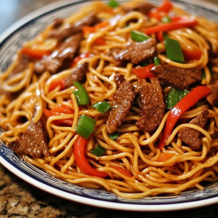 a plate full of noodles with beef and peppers