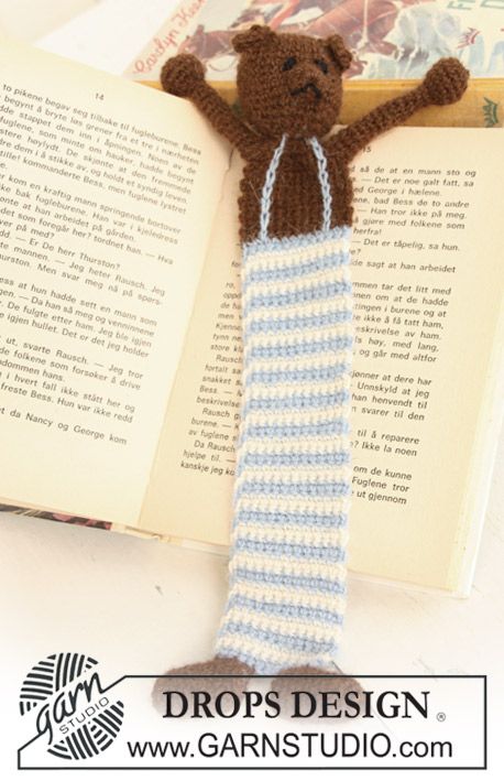 a crocheted teddy bear laying on top of an open book with its arms in the air