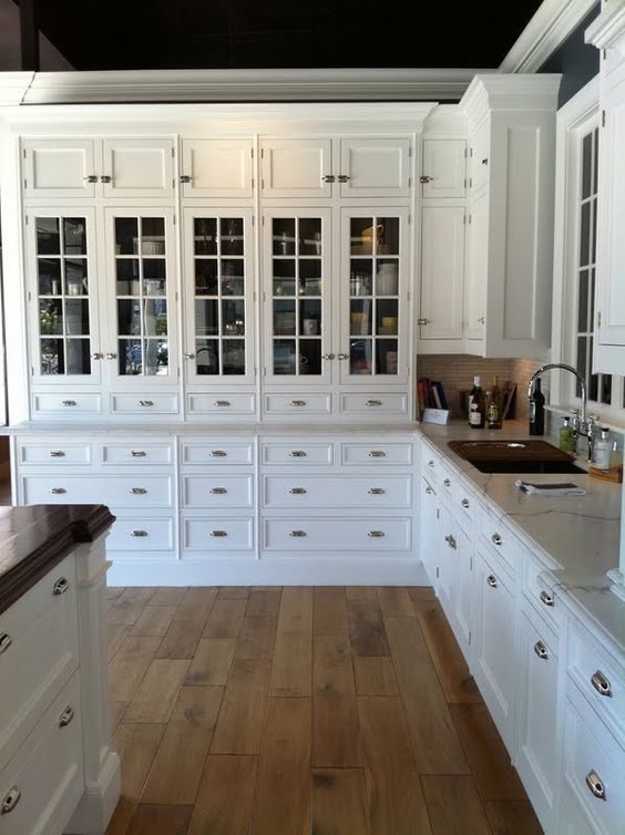 a kitchen with white cabinets and wood floors