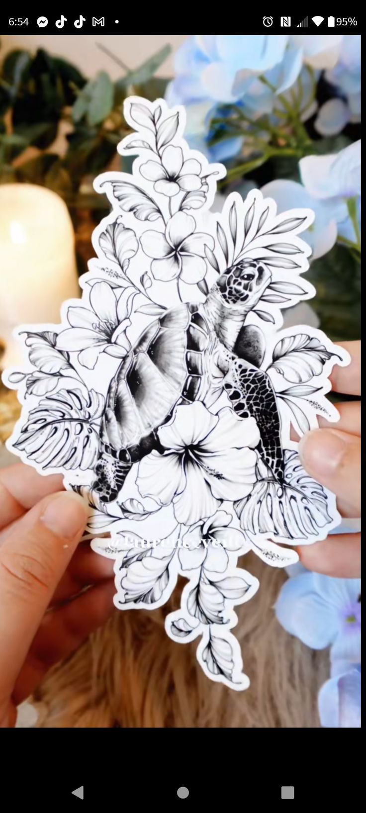 a person holding up a sticker with flowers on it and a bird in the middle