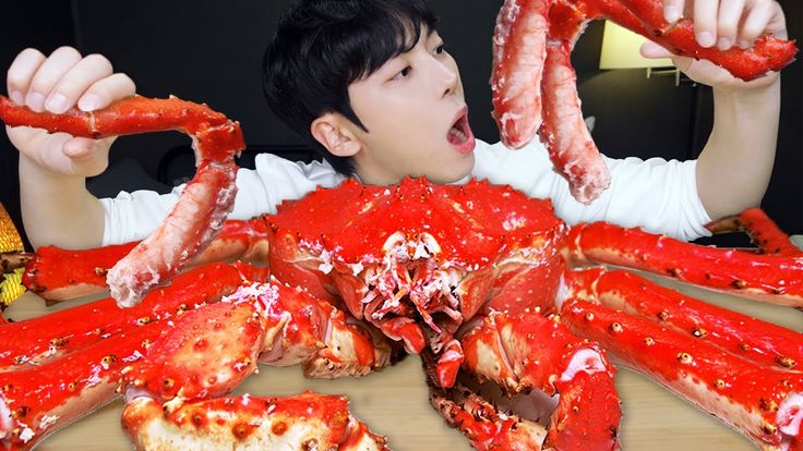 a young boy holding up two large red crabs